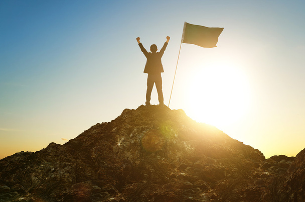 Silhouette of businessman with flag on mountain top - Foto, immagini