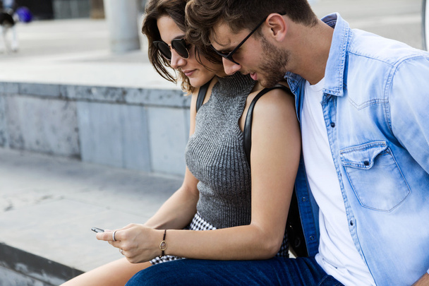 Happy young couple using mobile phone in the street. - Foto, imagen