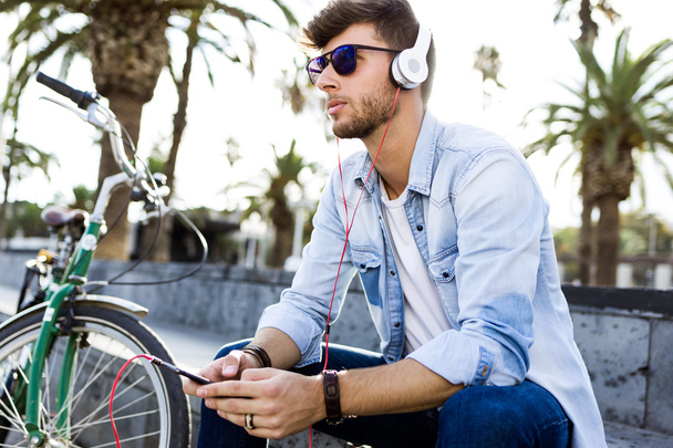 Handsome young man listening to music in the street. - Photo, Image
