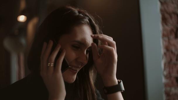 Vrouw beantwoordt de oproep praten aan de telefoon bij loft café close-up portret. 4k - Video