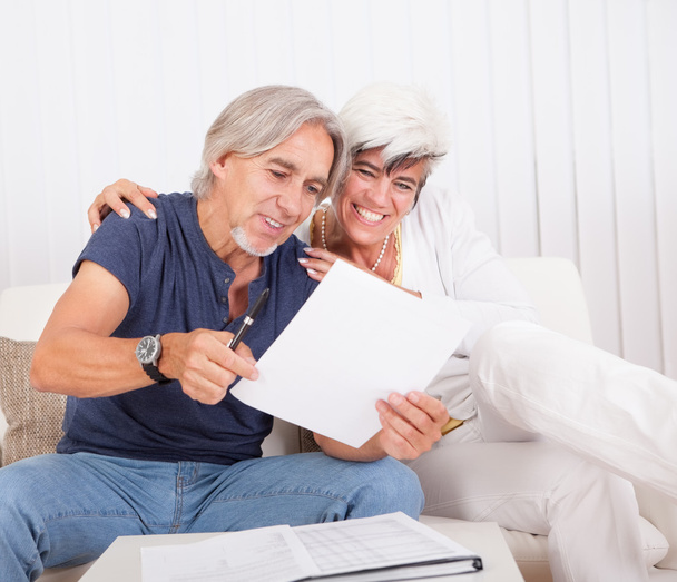 Emocionado documento de leitura de casal de meia-idade
 - Foto, Imagem