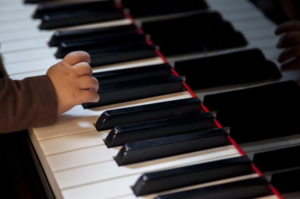 mano de niño recién nacido tratando de tocar el piano
 - Foto, imagen
