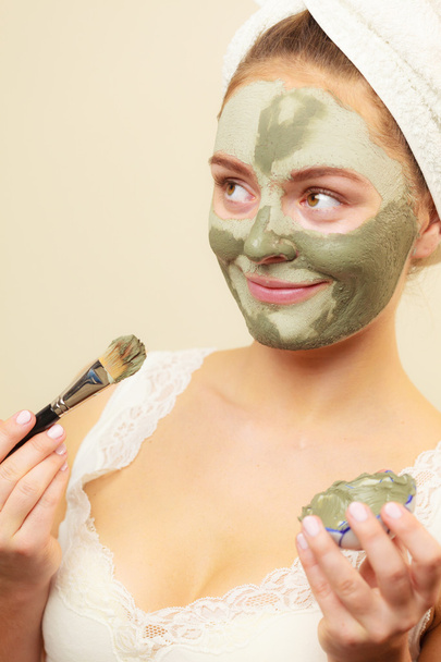 Vrouw met borstel klei modder masker toepassen op haar gezicht  - Foto, afbeelding