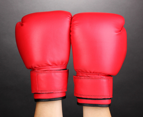 Red boxing gloves on hands on grey background - Фото, изображение