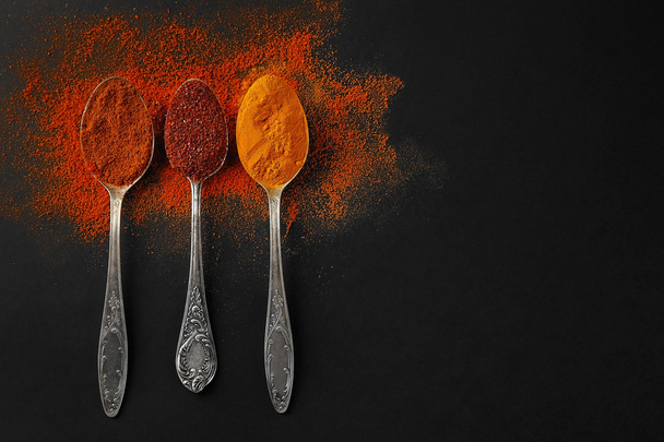 Spices in  spoons on a dark background - Foto, afbeelding