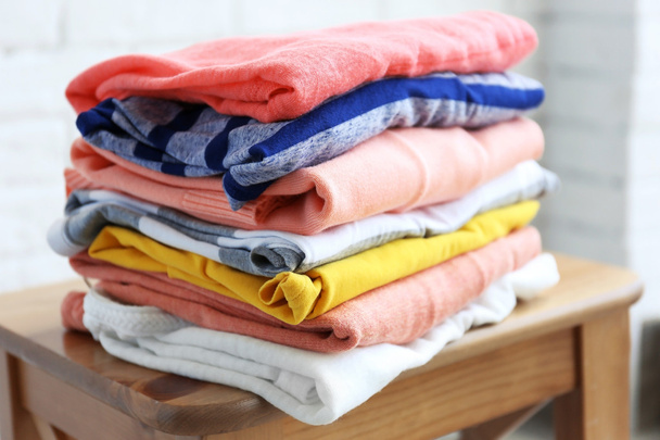 Pile of clothes on wooden stool, closeup - Foto, imagen