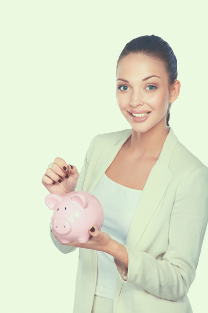 Young beautiful woman standing with piggy bank money box, isolated on white background - Фото, изображение