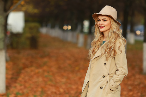 Hermosa mujer elegante de pie en sombrero beige de moda en un parque en otoño. espacio libre
. - Foto, Imagen