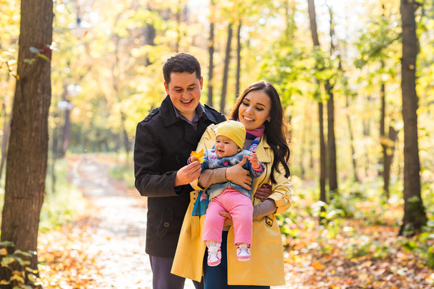 Familia joven y feliz con su hija pasando tiempo al aire libre en el parque de otoño
 - Foto, Imagen