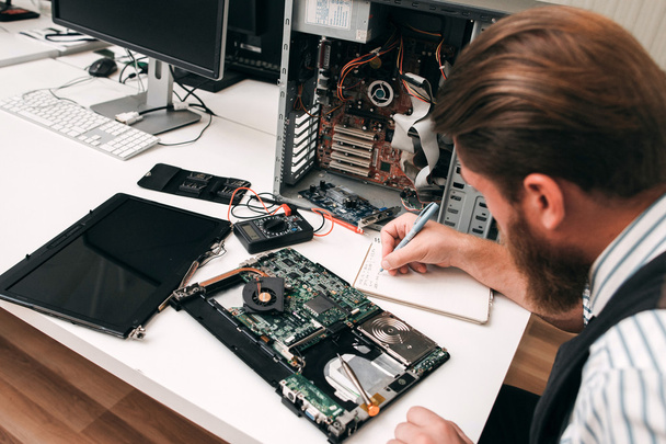 Bearded programmer inspecting computer motherboard - Photo, image
