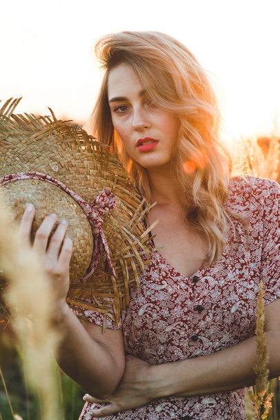Beautiful woman in field at summer sunset - Фото, изображение