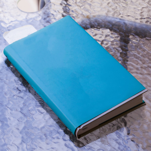 Blue book over glass table - 写真・画像
