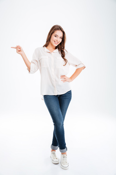 Full length portrait of a happy woman pointing finger away - Foto, imagen