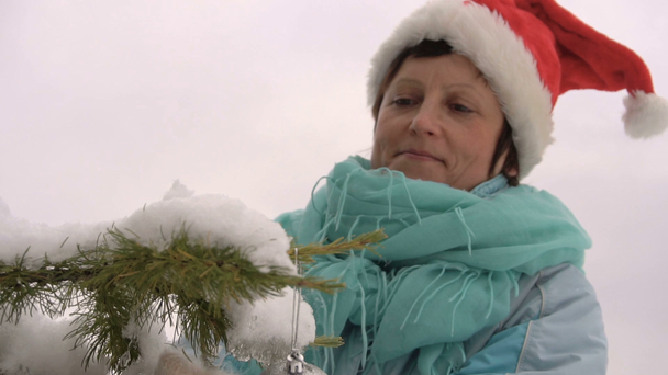 Mujer de Santa Sombrero Decora un Árbol de Navidad en el Bosque Slow Motion
 - Metraje, vídeo