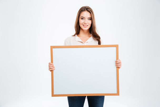 Portrait of a smiling young woman showing blank board - Photo, Image