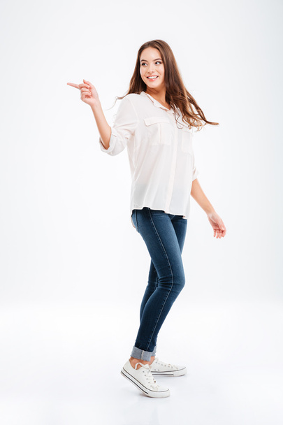 Full length portrait of a happy woman pointing finger away - Фото, изображение