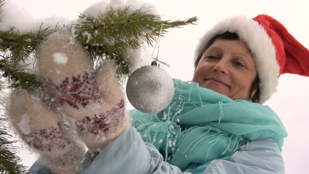Mujer de Santa Sombrero Decora un Árbol de Navidad en el Bosque Slow Motion
 - Imágenes, Vídeo