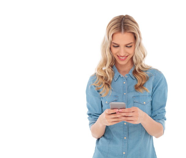 Lächelnde blonde Frau liest SMS auf ihrem Smartphone - Foto, Bild