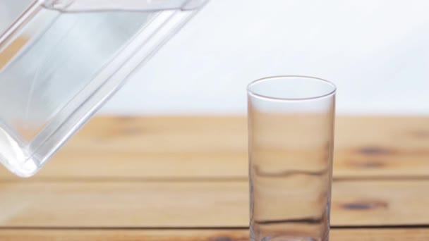 Νερό χύνοντας σε γυαλί σε ξύλινο τραπέζι - Πλάνα, βίντεο