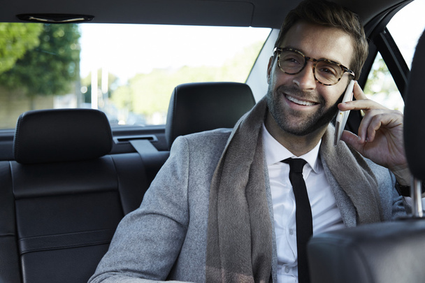 Uomo d'affari in auto che prende chiamata su smartphone
 - Foto, immagini