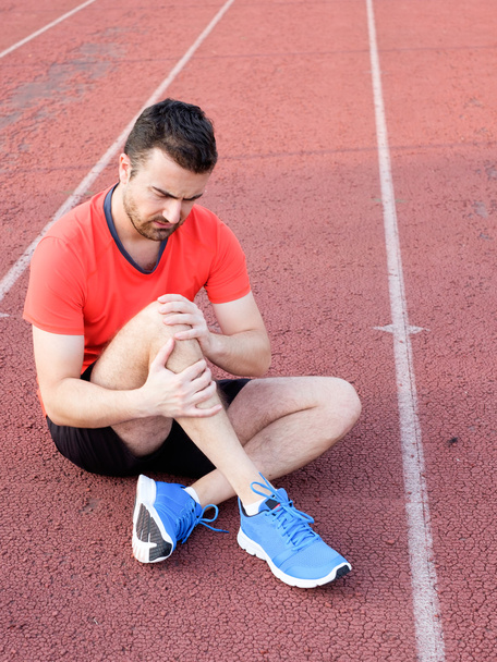 Runner with injured knee on the track - Foto, immagini