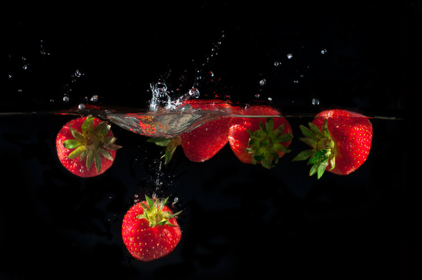 Strawberries splashing into water  - Фото, изображение