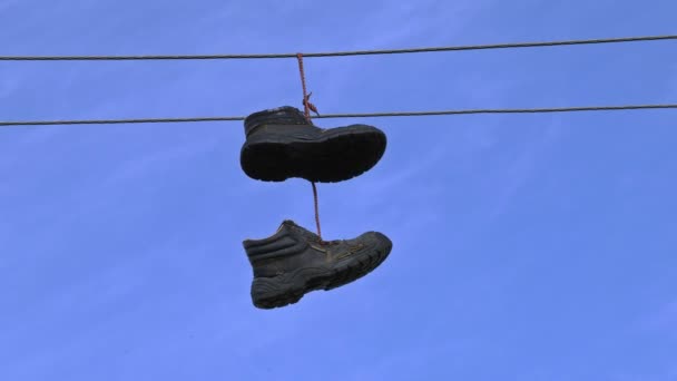 alte Stiefel hängen an einem elektrischen Draht am blauen Himmel  - Filmmaterial, Video