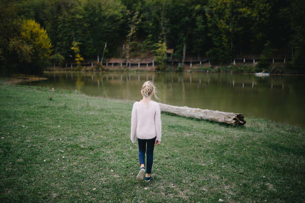 sad little girl goes alone on the shore of the lake - Photo, Image