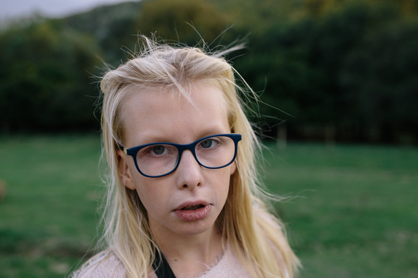 Portrait of a sad blonde girl with glasses outdoors in the park - Zdjęcie, obraz