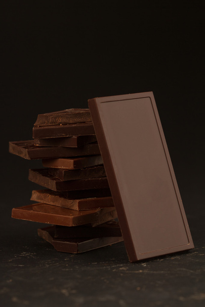 Vierkant gevormde chocoladestukjes op donkere achtergrond - Foto, afbeelding