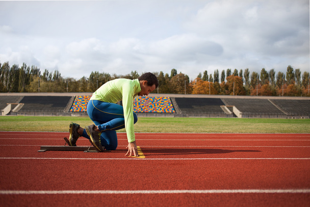 Nuori urheilullinen mies on valmis juoksemaan kilparadalla. suuri mukava moderni stadion
 - Valokuva, kuva