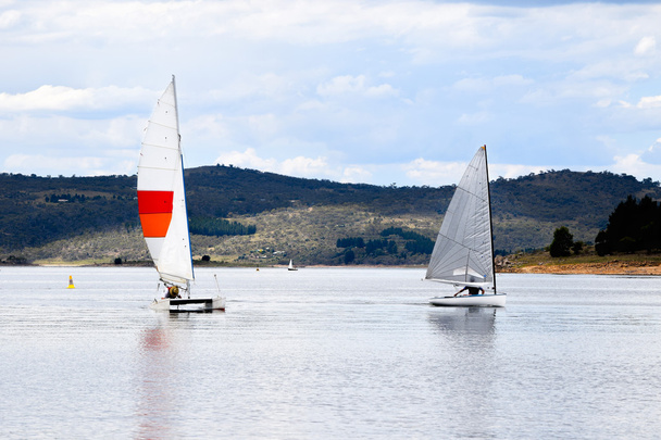 Kaksi purjeveneitä paikallisen rodun järvellä juurella vuorijono
 - Valokuva, kuva