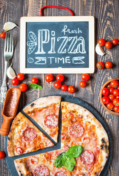 Hot Italian pizza on a rustic wooden table. - Фото, изображение