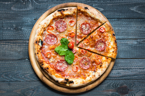 Hot Italian pizza on a rustic wooden table. - Photo, Image