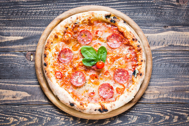 heiße italienische Pizza auf rustikalem Holztisch. - Foto, Bild