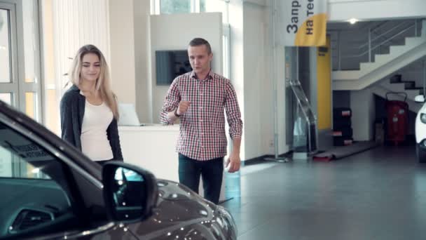 Myyjä puhuu pariskunnalle autokaupan sisällä
 - Materiaali, video