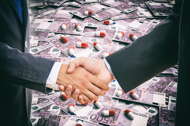 Handshake on pills and banknotes background - Photo, Image