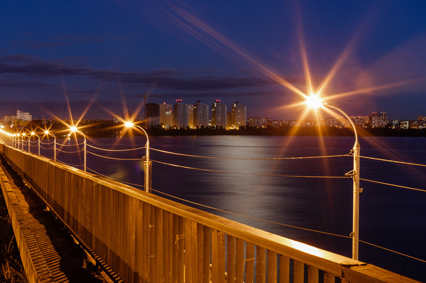 Noc widok z mostu nad jeziorem i od domów - Zdjęcie, obraz