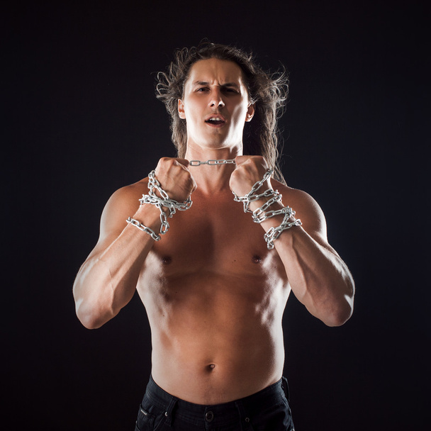 Young man with long hair breaks the iron chain. Strong. Concept of resistance - Fotoğraf, Görsel