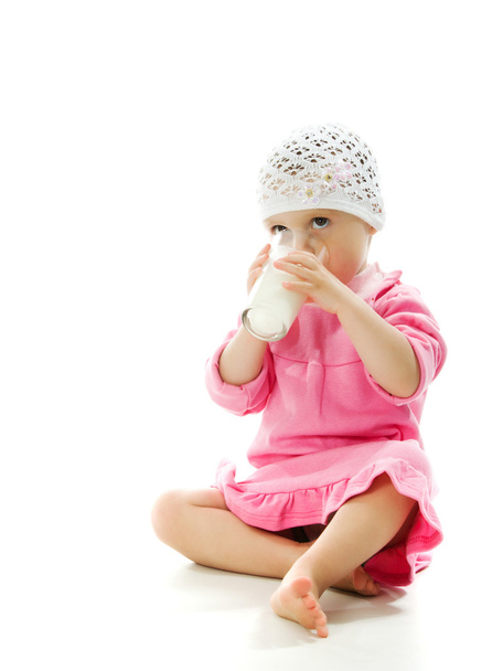 A pretty little girl is holding a glass of milk isolated on the white background - Zdjęcie, obraz
