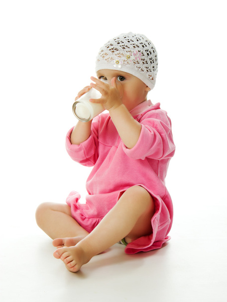 A pretty little girl is holding a glass of milk isolated on the white background - Photo, image