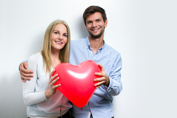 Jovem casal sorrindo e segurando um coração
 - Foto, Imagem