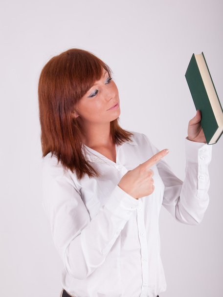 A young beautiful woman is holding up a book - Foto, afbeelding