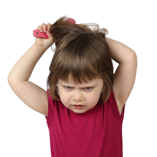Angry little girl combs her hair - 写真・画像