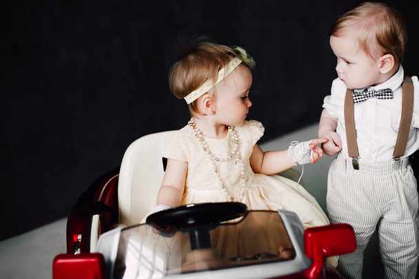 mariage de deux bébés - garçon et fille habillés en mariés jouant avec une voiture jouet
 - Photo, image