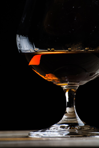 Bohemian glass of cognac on a wooden table - Foto, afbeelding