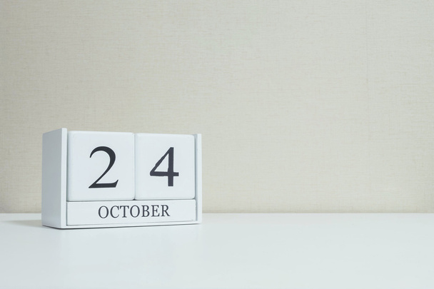 Gros plan calendrier en bois blanc avec noir 24 mot d'octobre sur le bureau en bois blanc flou et papier peint de couleur crème dans la chambre fond texturé avec espace de copie, mise au point sélective au calendrier
 - Photo, image