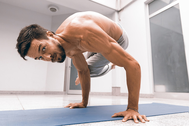 Athletic strong man practicing difficult yoga pose. - Φωτογραφία, εικόνα
