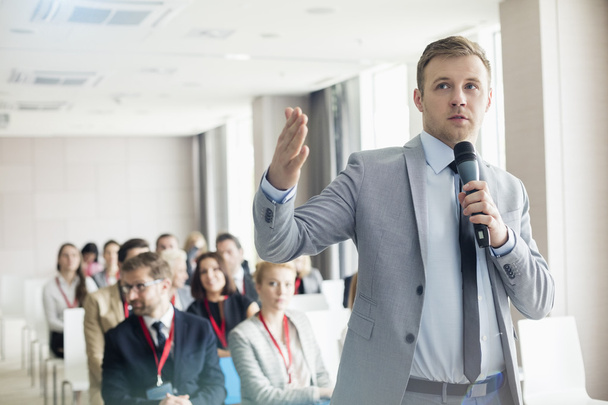 Businessman speaking through microphone during seminar - Fotó, kép