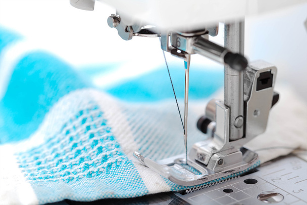 Máquina de coser primer plano con tela azul sobre fondo blanco
 - Foto, Imagen